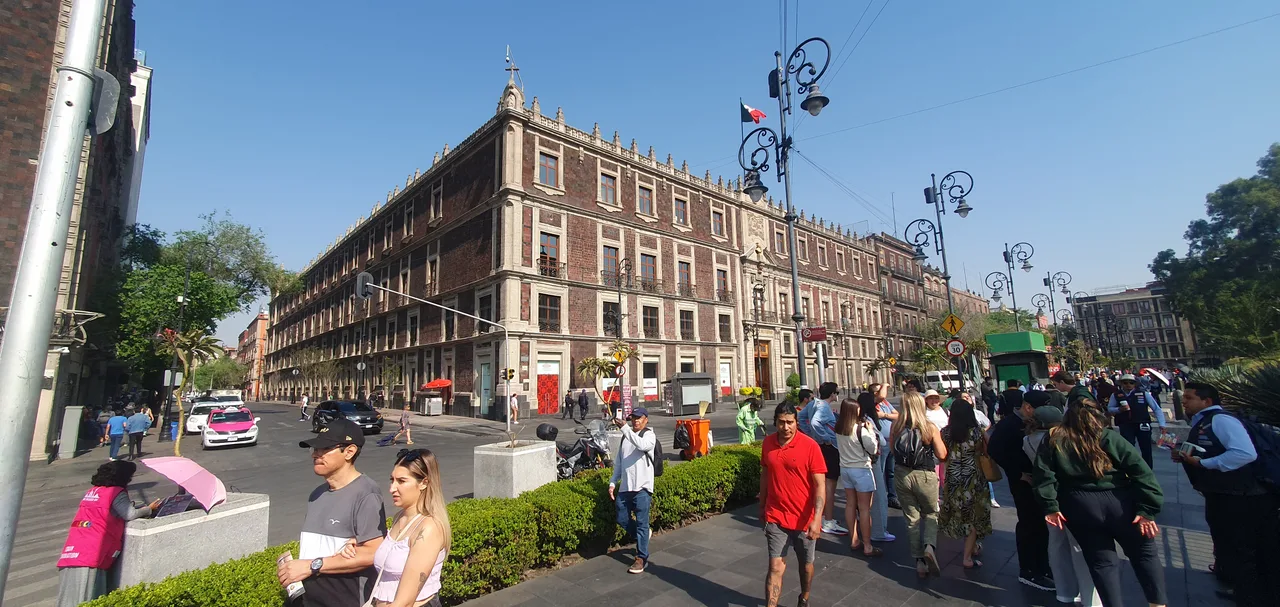 Nacional Monte de Piedad Fachada de piedra clara de un edificio colonial de dos pisos con arcos y balcones, ocupando una esquina frente a una plaza