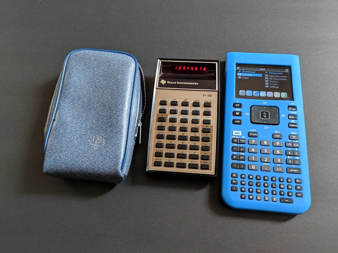 Dos generaciones de calculadoras Una calculadora Texas Instruments TI-30 de LED rojo junto a su funda azul y una calculadora gráfica TI-Nspire azul